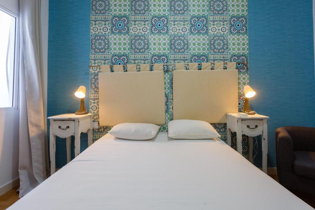 加的斯Apartamentos El BALNEARIO by Cadiz4Rentals的一间卧室配有一张带两张桌子和两盏灯的床。
