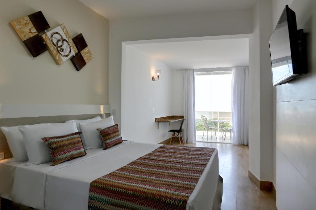 维多利亚Transamerica Fit Vitória Praia de Camburi的卧室设有一张白色大床和一扇窗户。