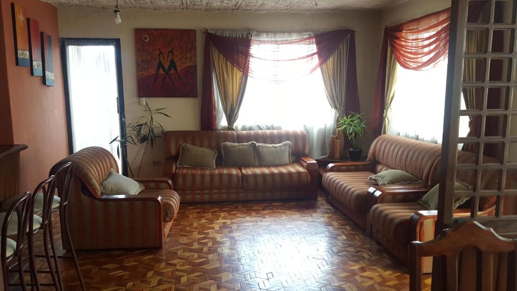 昆卡La Muralla的客厅配有两张真皮沙发和两扇窗户