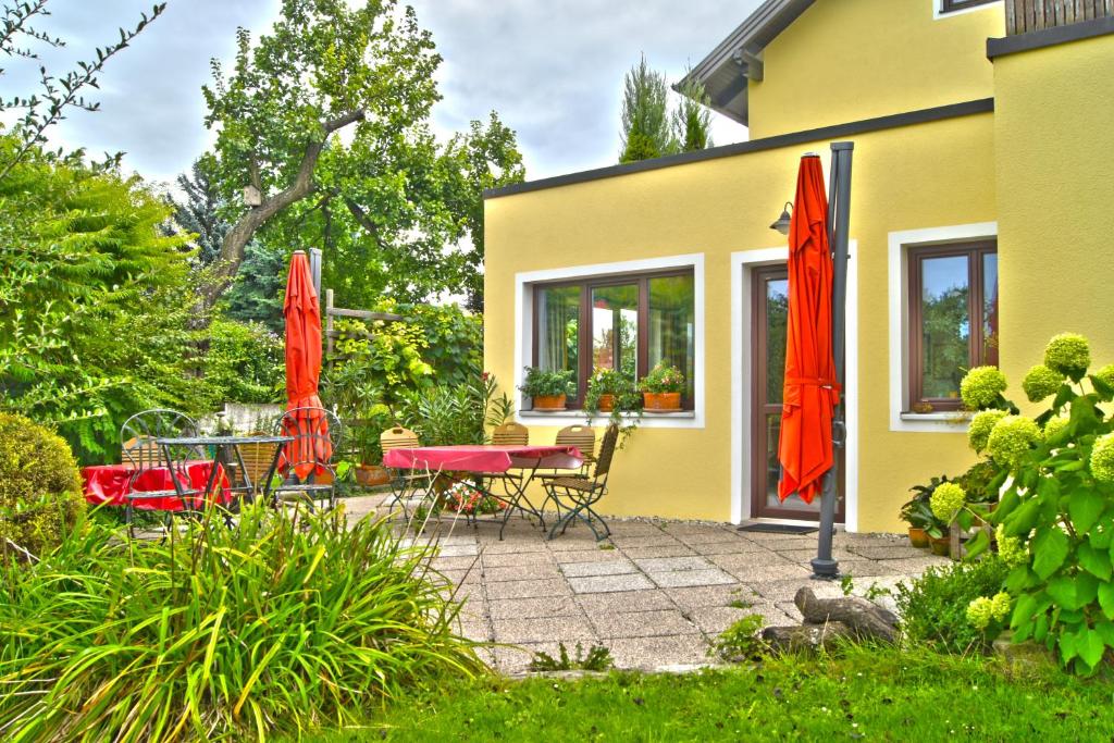 毛特恩Gästezimmer Ilse Brauneis的一个带红色遮阳伞和桌椅的庭院