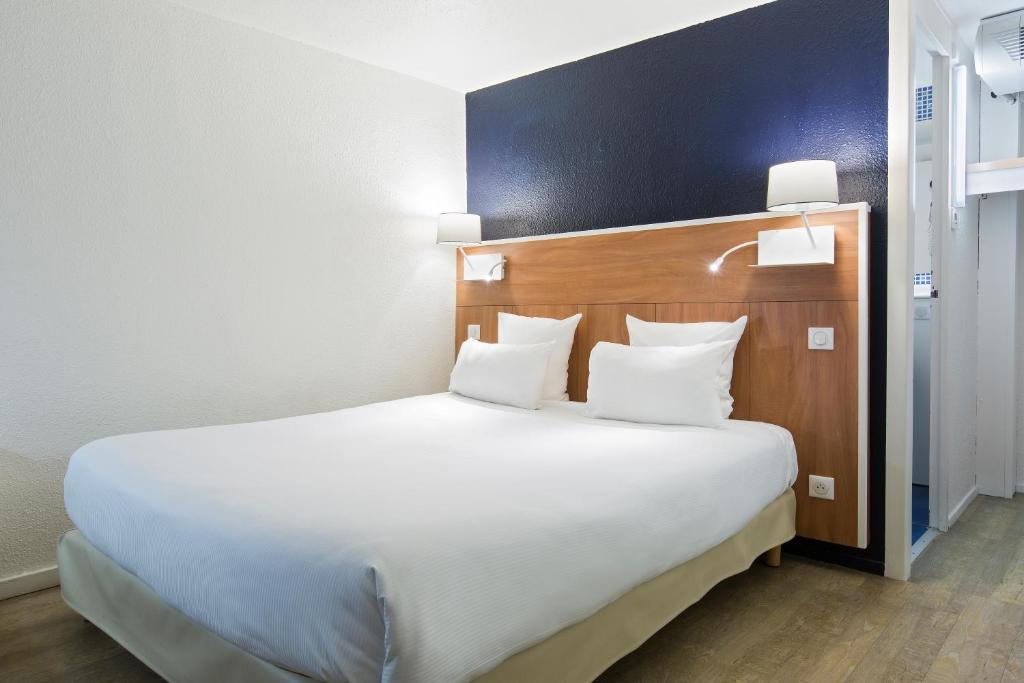朗吉斯Comfort Hotel ORLY-RUNGIS的卧室配有带白色枕头的大床