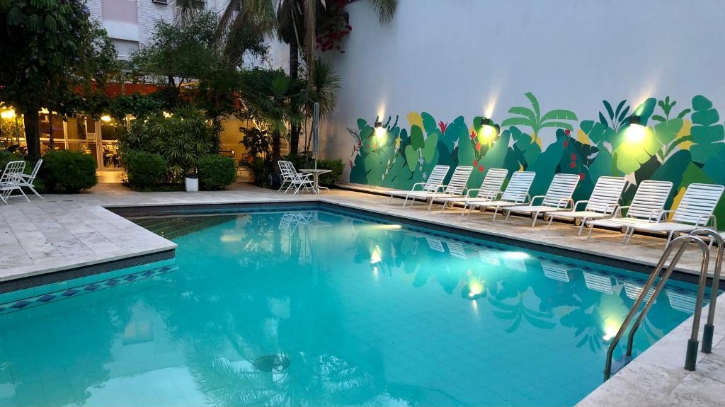 门多萨奴提步瑞酒店的一个带椅子的游泳池和一个带壁画的墙壁