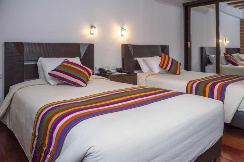 拉巴斯卡索那精品酒店的酒店客房配有两张带彩色条纹枕头的床