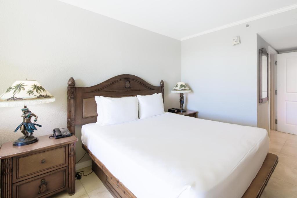 檀香山Luana Waikiki #710的一间卧室配有一张大床和一个带灯的床头柜