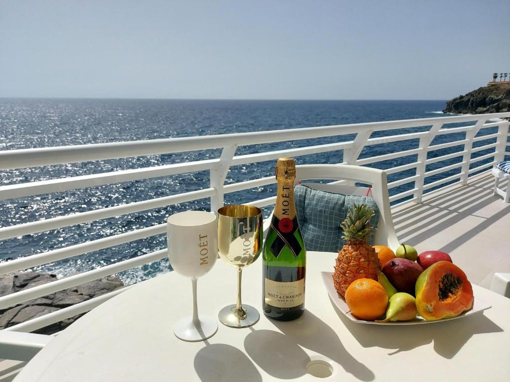 卡亚俄萨尔瓦赫Love boat deluxe experience的一张桌子,上面放着一盘水果和一瓶葡萄酒