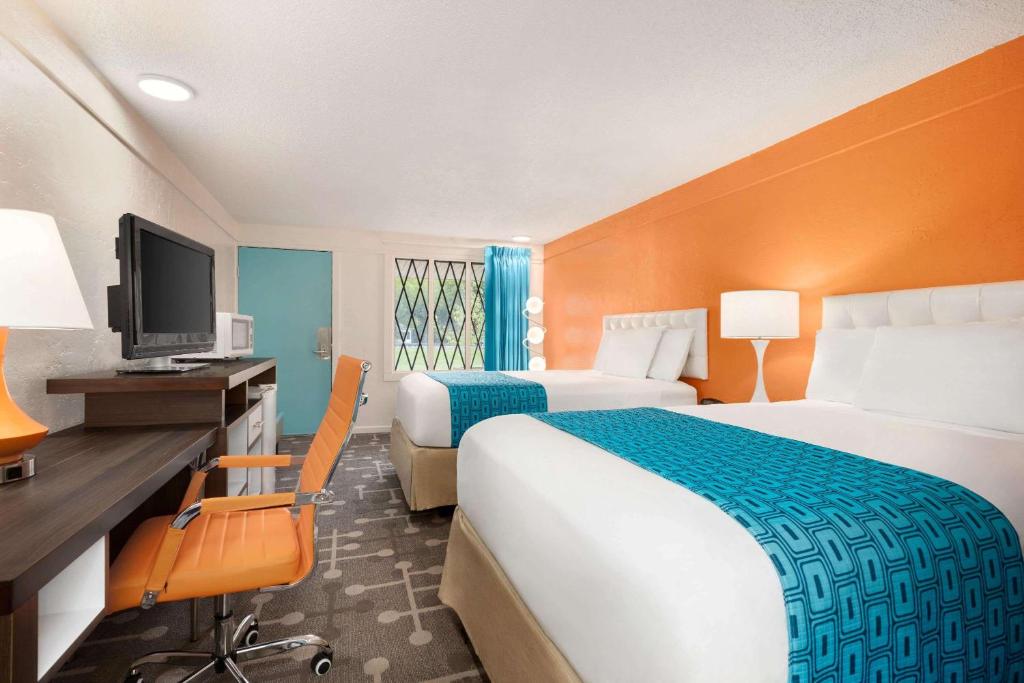 DoverDover Inn and Suites的酒店客房设有两张床、一张桌子和一台电视。