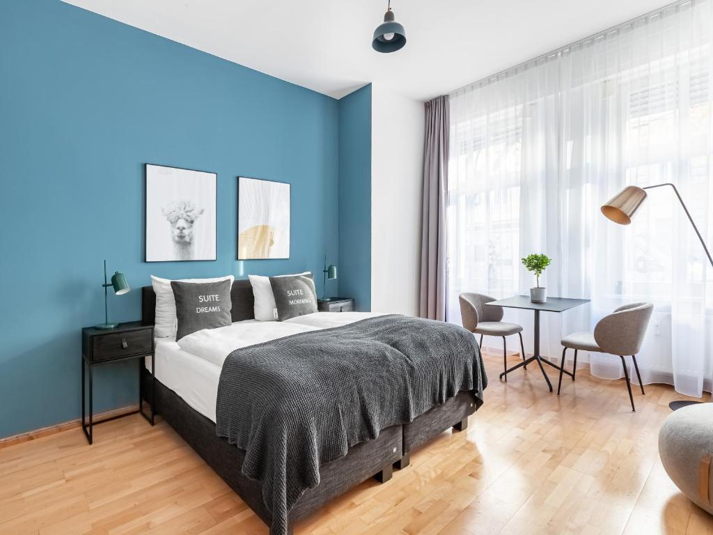 柏林limehome Berlin Malmöer Straße的一间拥有蓝色墙壁的卧室,配有一张床和一张桌子