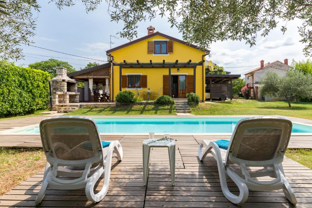 布耶Villa Nada的黄色房屋 - 带两把椅子和游泳池