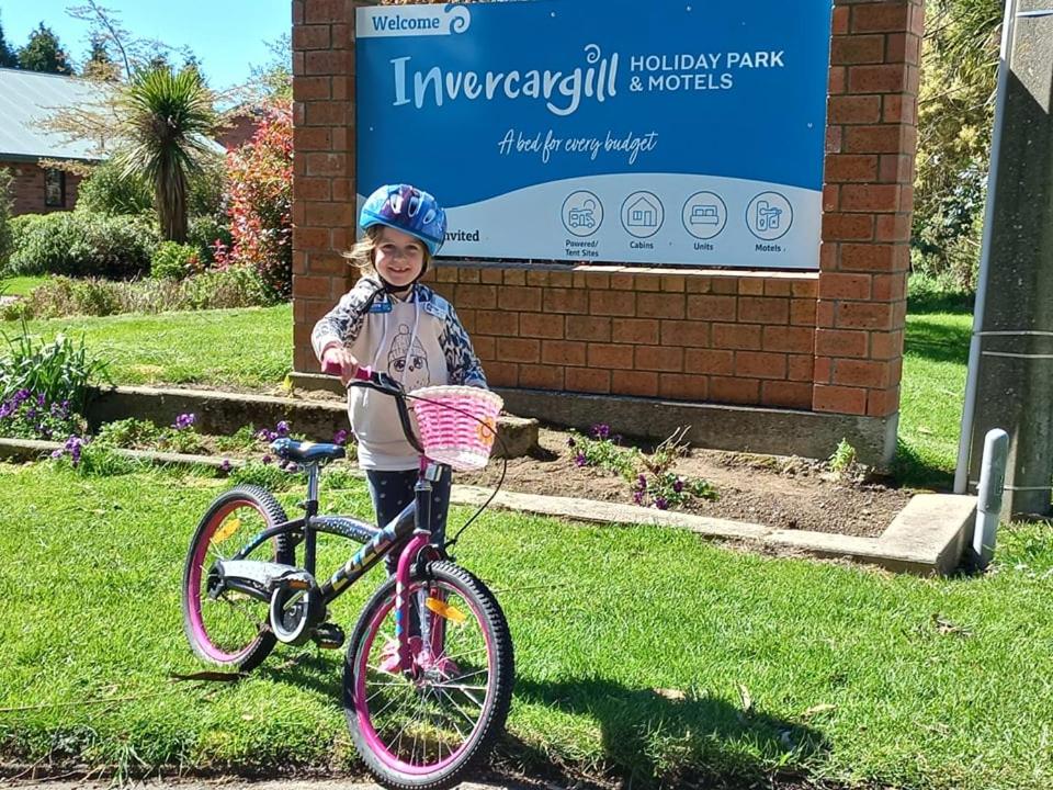 因弗卡吉尔Invercargill Holiday Park & Motels的一个小女孩站在自行车旁边