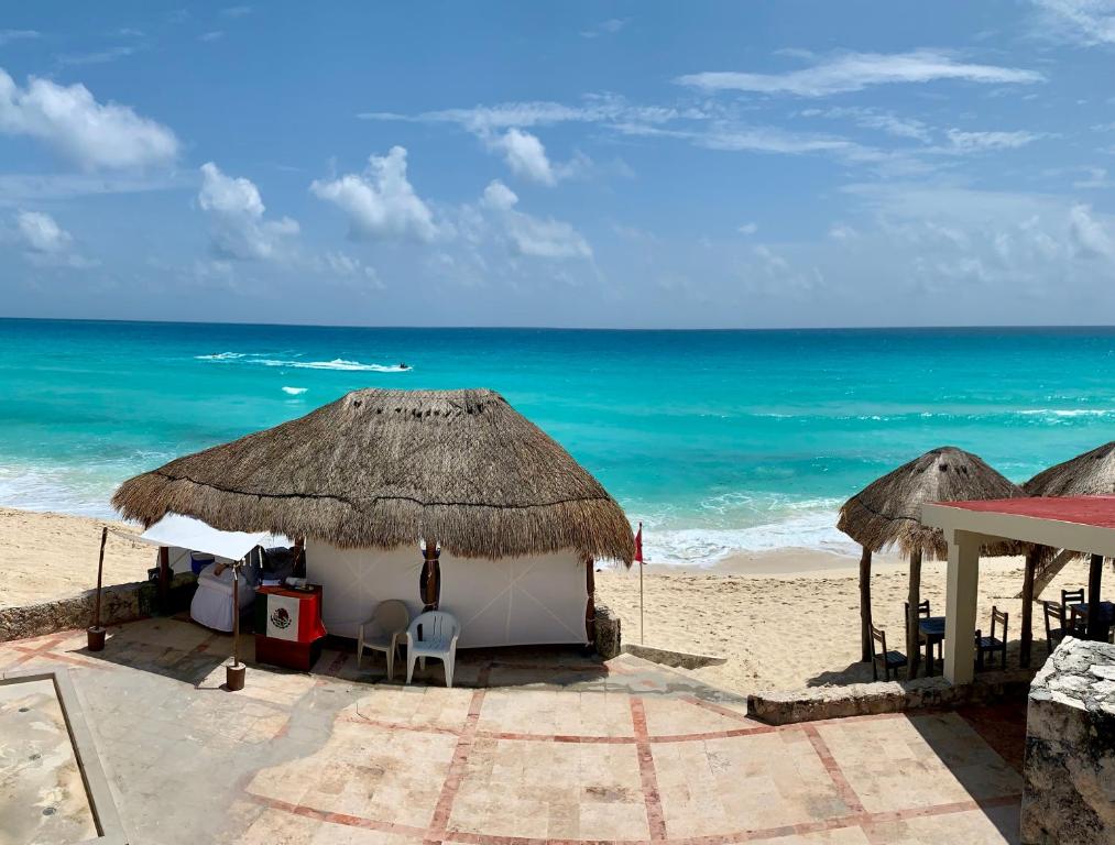 坎昆Preciosos Estudio Vista al Mar o jardín的海滩上设有椅子和遮阳伞,还有大海
