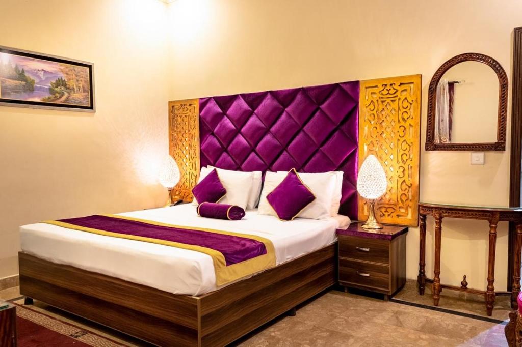 拉合尔Rose Palace Hotel, Gulberg的一间卧室配有一张大床和紫色床头板