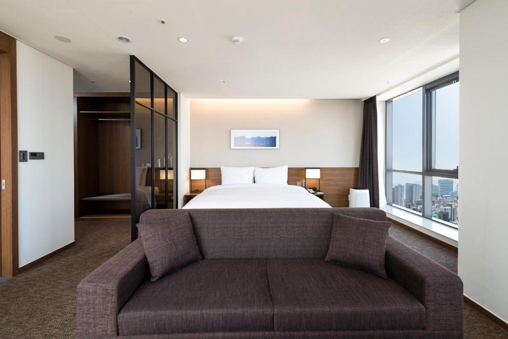 釜山Ramada Encore by Wyndham Busan Haeundae的酒店客房,配有床和沙发