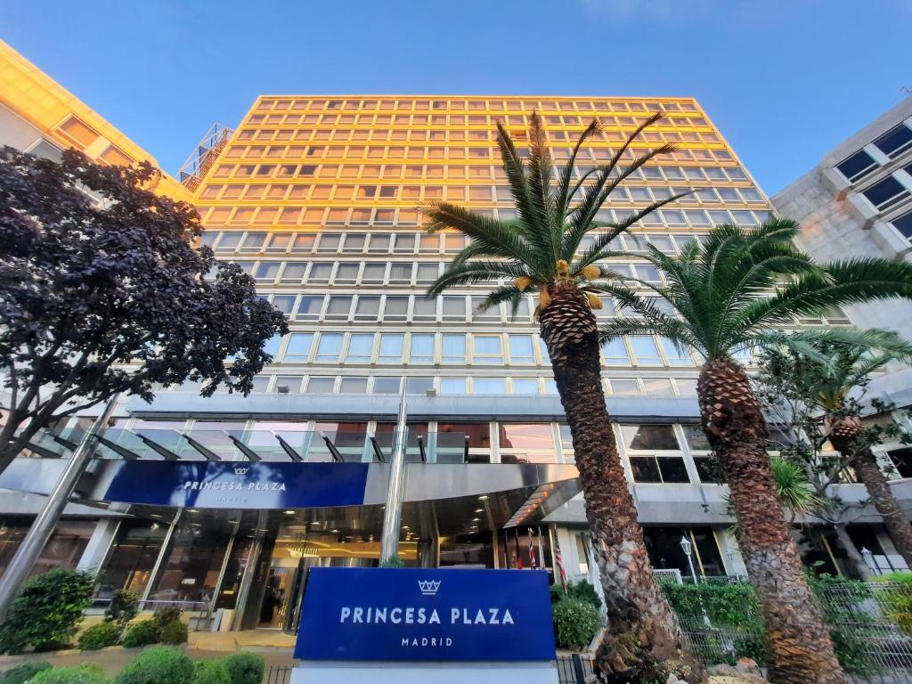 马德里Hotel Princesa Plaza Madrid的两棵棕榈树的建筑