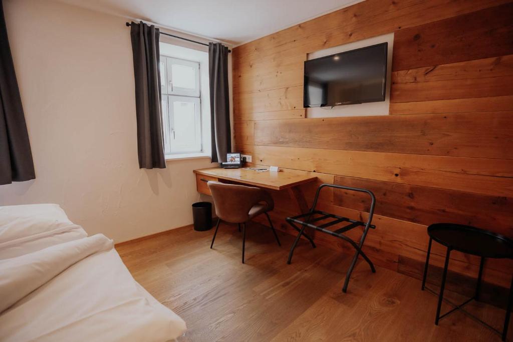 丁克尔斯比尔Altstadtmittehotel Sonne的一间卧室配有书桌,木墙上配有电视。