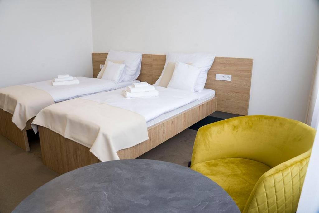 特雷比绍夫Wellness hotel Mestská plaváreň的带两张床和黄色椅子的房间