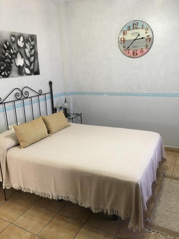 埃尔卡斯蒂略德拉斯瓜尔达斯阿巴荷乡村旅馆的一间卧室设有两张床,墙上挂着一个时钟。