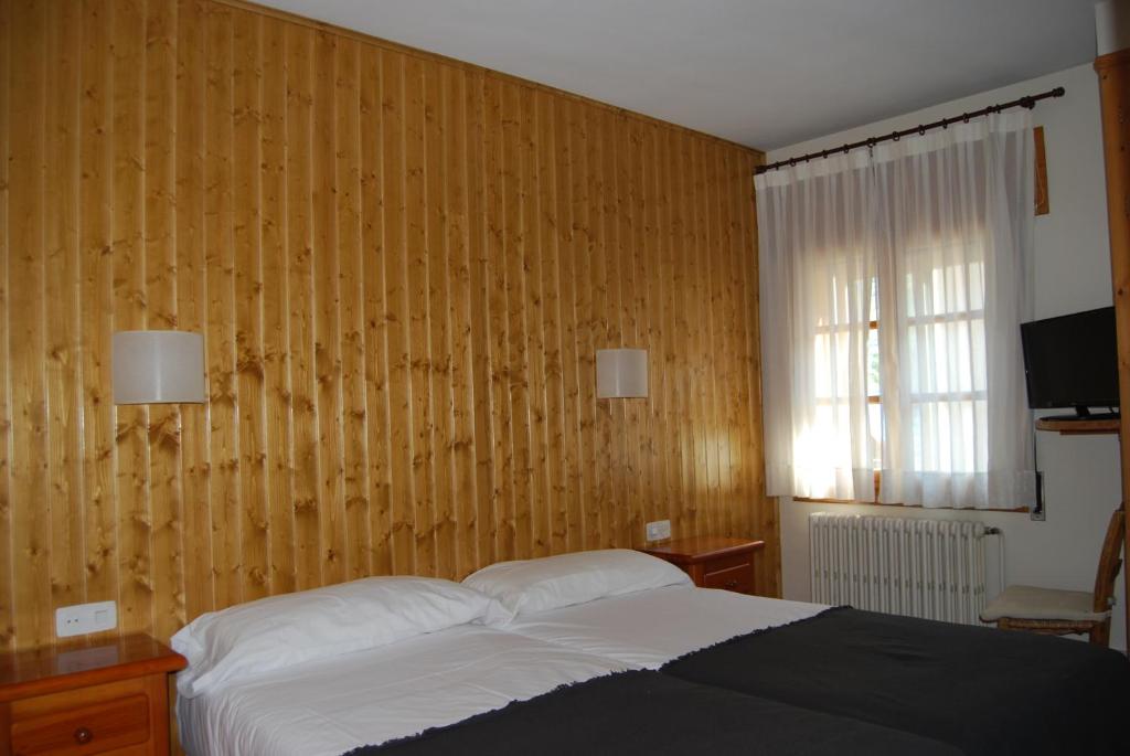 维耶拉卡萨维森塔旅馆的一间卧室设有一张床和木墙