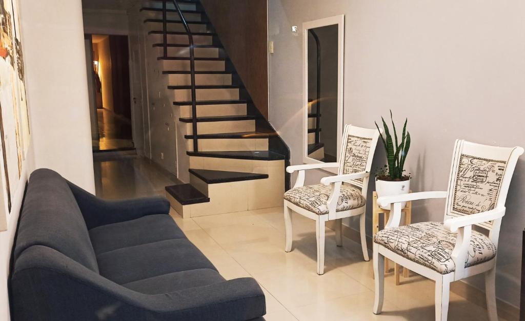 布拉加多Hotel Miceli的客厅配有沙发和两把椅子,设有楼梯