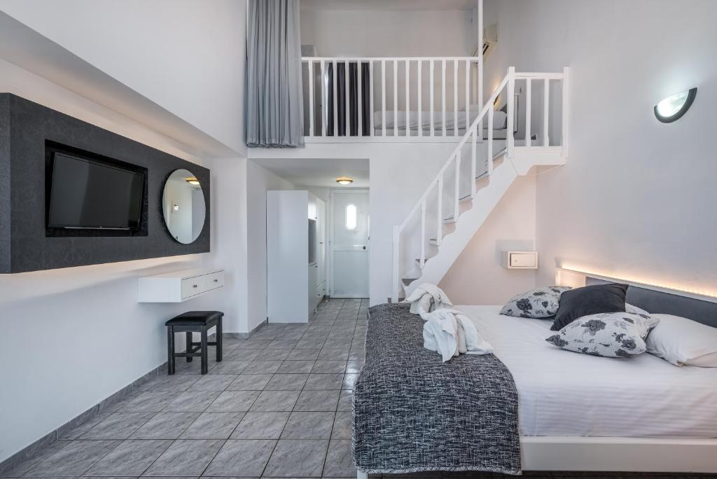 蒂加基ILIOS K Village Resort的一间卧室设有床铺、电视和楼梯。