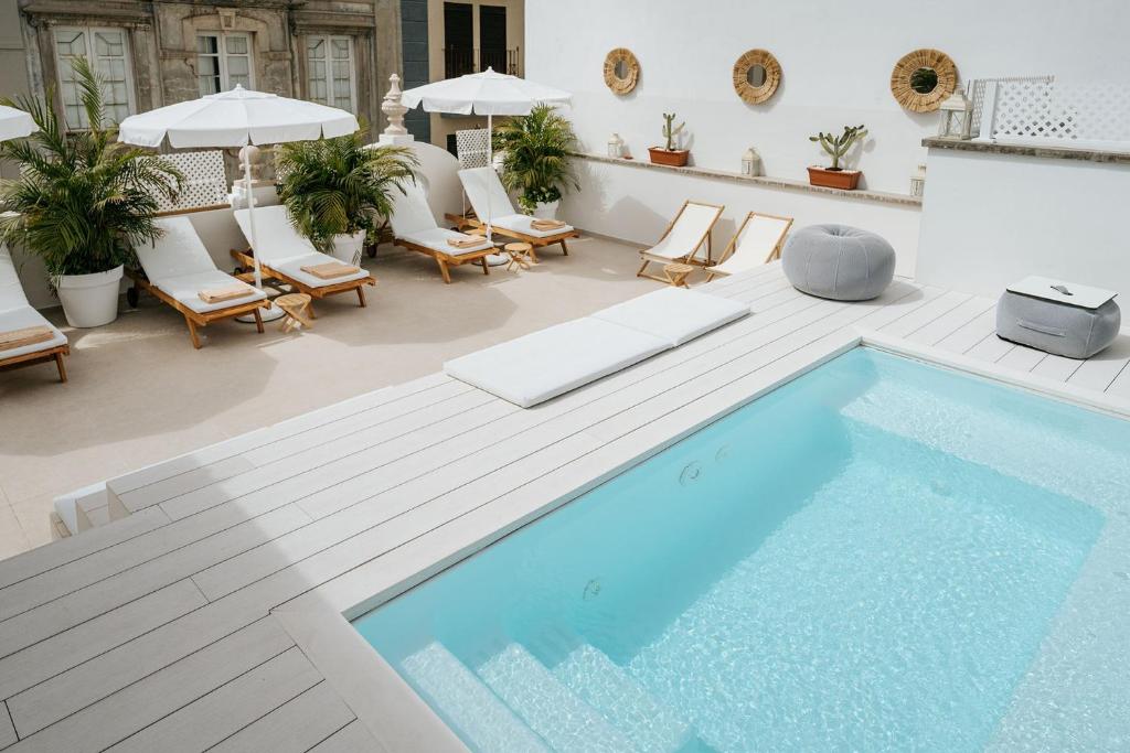 圣克鲁斯-德特内里费Emblemático F24-Only Adults B&B的一个带椅子的庭院的游泳池和一个游泳池
