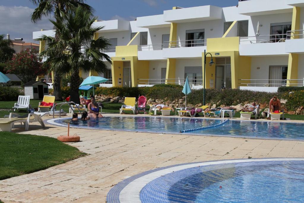 阿尔沃尔Apartamentos Santa Teresinha的一个带游泳池的度假村,那里有椅子
