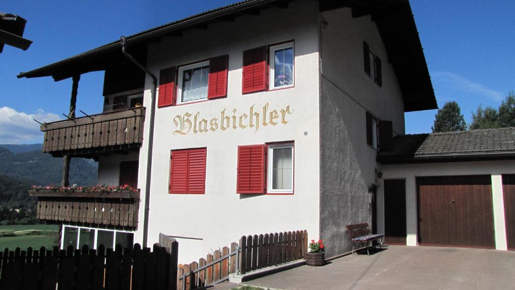 布鲁尼科Blasbichler Appartments的白色的房子,有红色百叶窗和栅栏