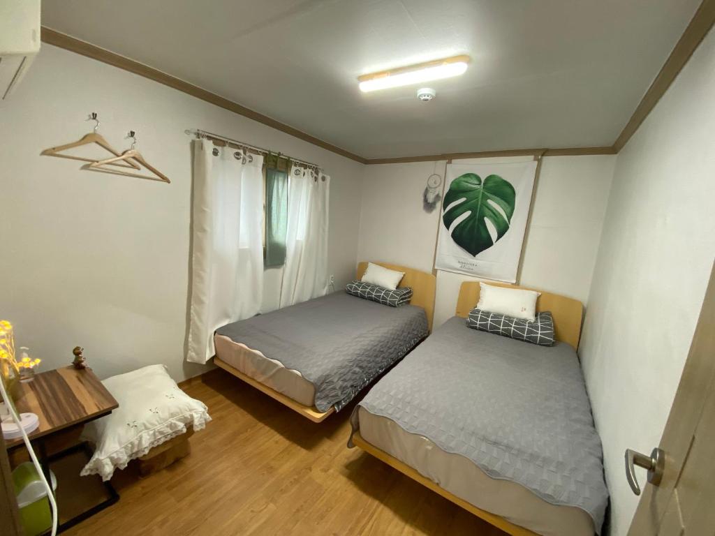 江陵市Saesori Guesthouse的一间卧室配有两张床、一张桌子和一张桌子