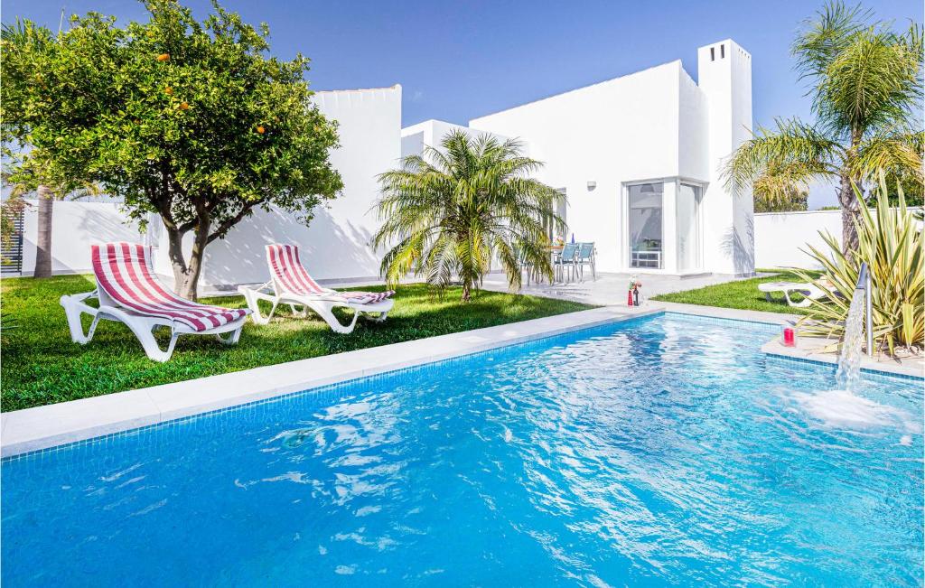 科尼尔-德拉弗龙特拉Lovely Home In Conil De La Frontera With Swimming Pool的一个带两把椅子的游泳池以及一座房子
