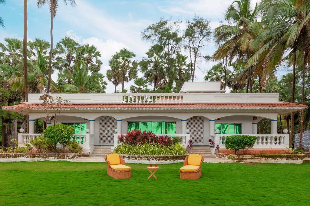 孟买StayVista's Villa Bharat - Beachfront serenity with A spacious lawn的院子里带椅子的白色房子