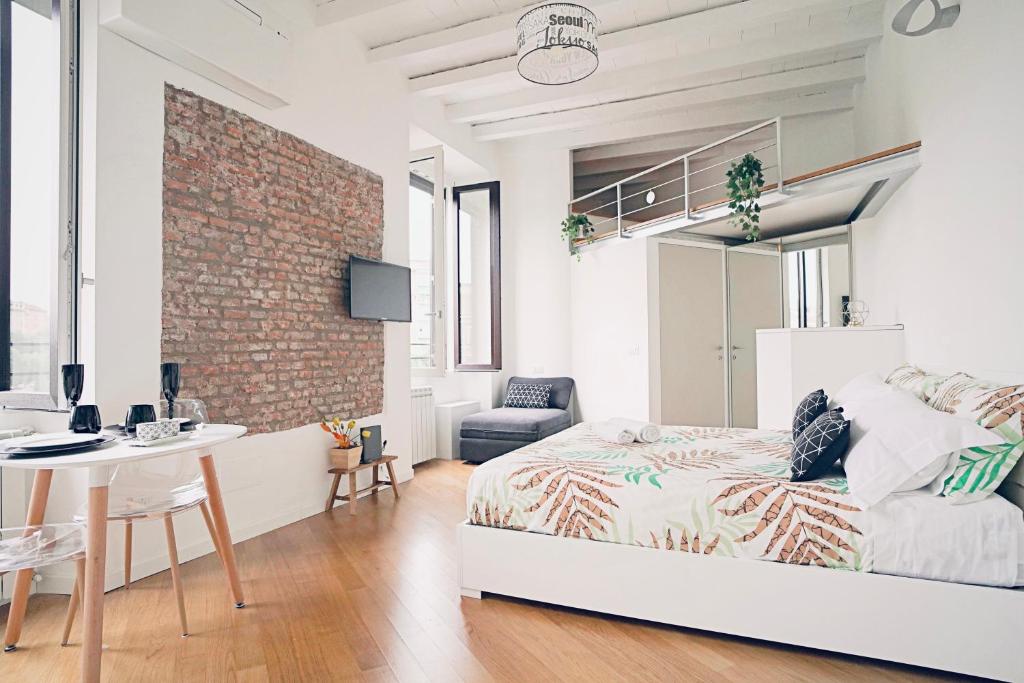 米兰P&D Apartments Darsena的一间卧室配有一张床、一张桌子和砖墙