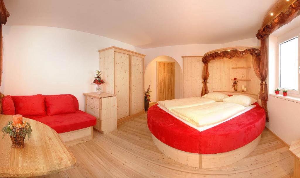 瑟尔Bed & Breakfast Landhaus Strasser的一间卧室配有一张大床和一张红色的沙发