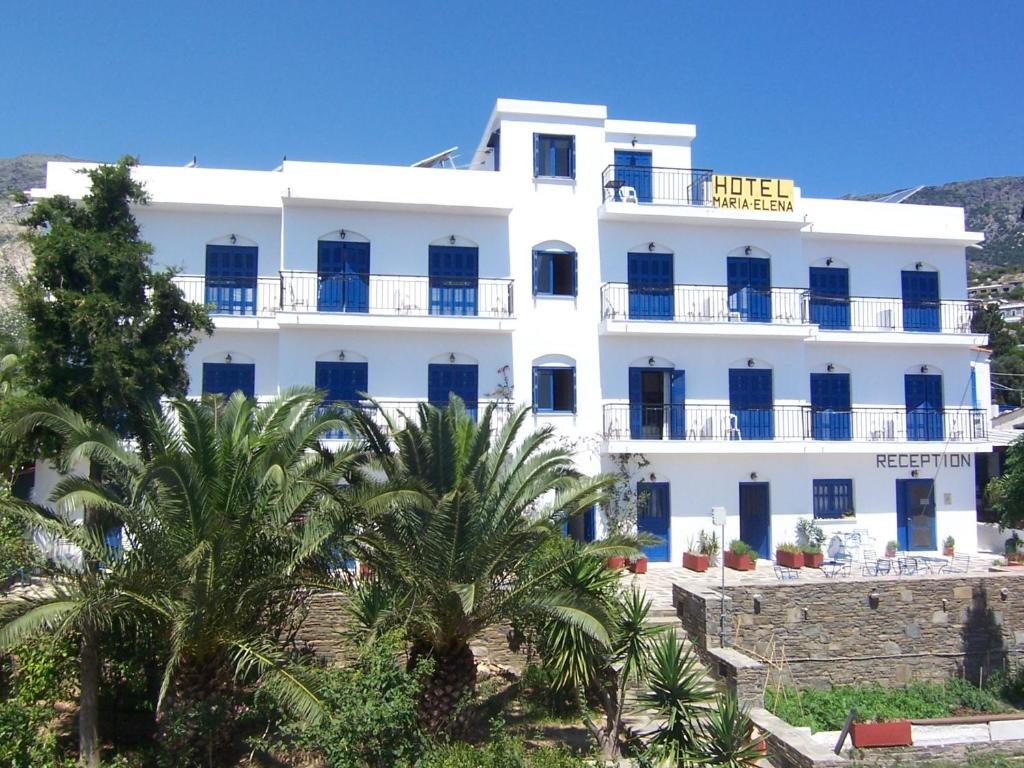 阿基奥斯基利考斯玛丽亚埃莱娜酒店的一座白色的建筑,前面有棕榈树