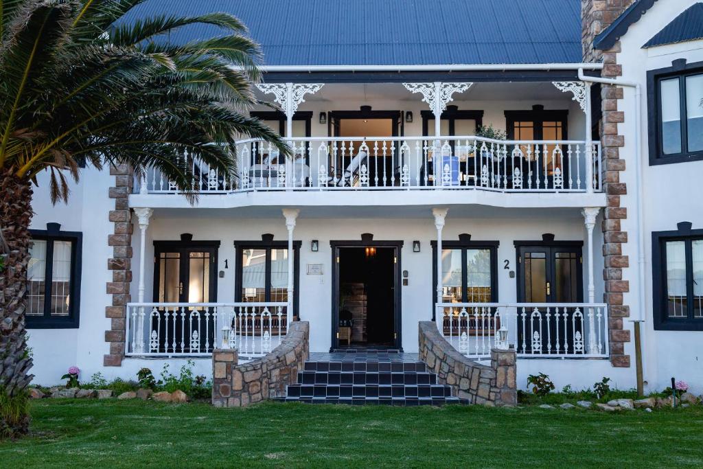 克莱因蒙德Villa Le Roc Kleinmond Accommodation的带阳台和门廊的白色房屋