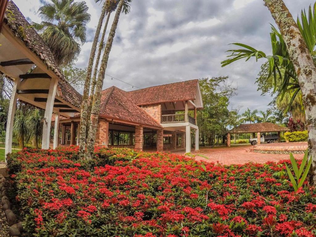 比亚维森西奥Hotel Hacienda Gualanday的前面有红花的房子