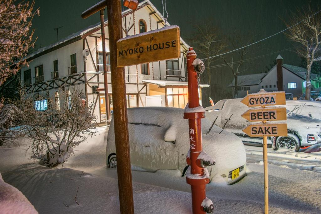 妙高Myoko House的房屋旁边的雪地里的一个街道标志
