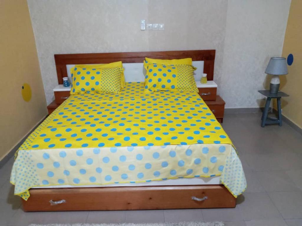 阿比让Beinvenue Chez-vous situé vers la nouvelle Route de Bengerville的一间卧室配有一张黄色和蓝色的波尔卡圆点床