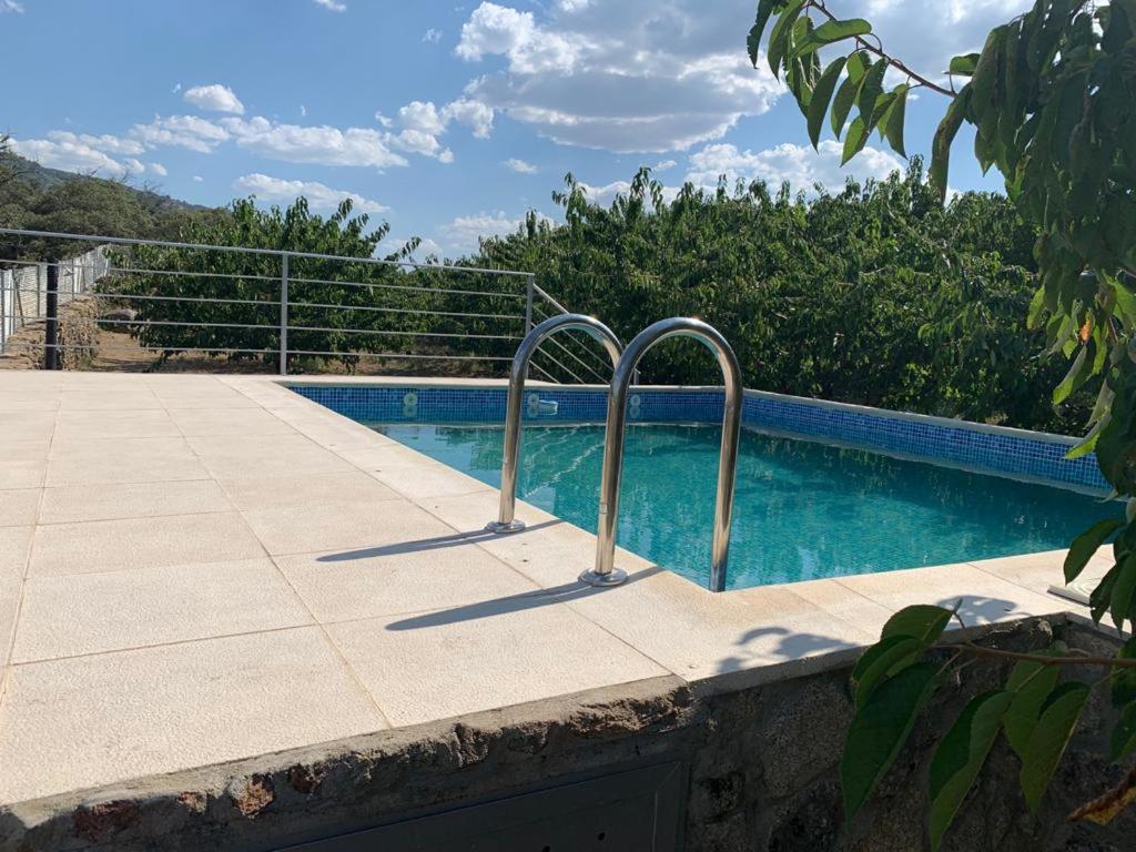 埃尔托尔诺Casa Rural Canchal Madroñeras ***的游泳池旁设有两个金属扶手