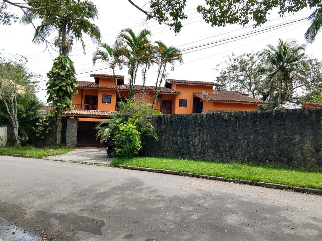 乌巴图巴Casa 5 suítes com piscina e churrasqueira的石墙和街道的房子
