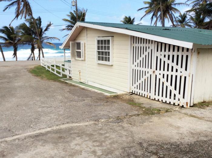 Saint Joseph休闲避风港海滩小屋旅馆的一座白色的小建筑,有大门和棕榈树