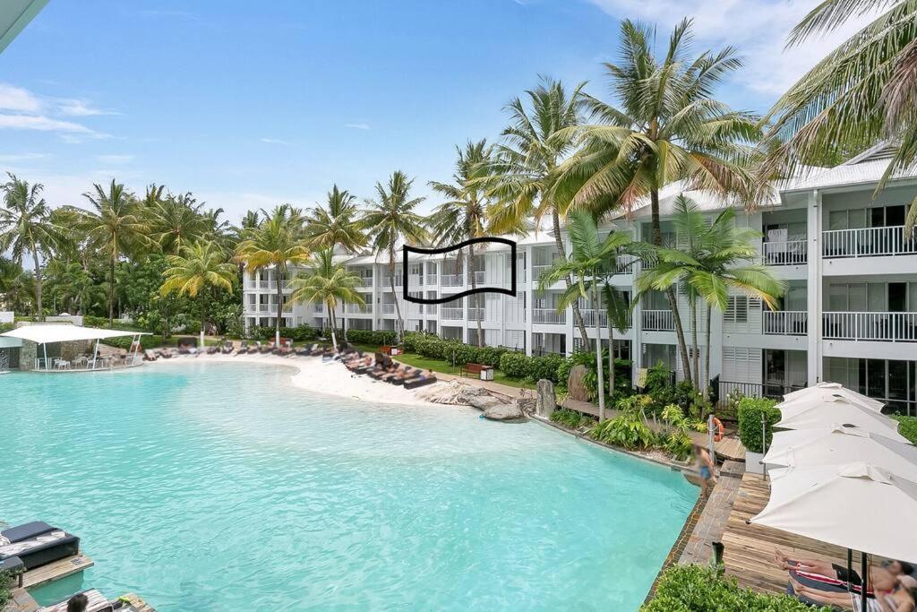 道格拉斯港Beach Club Port Douglas 3 Bedroom Penthouse的一座棕榈树游泳池和一座建筑