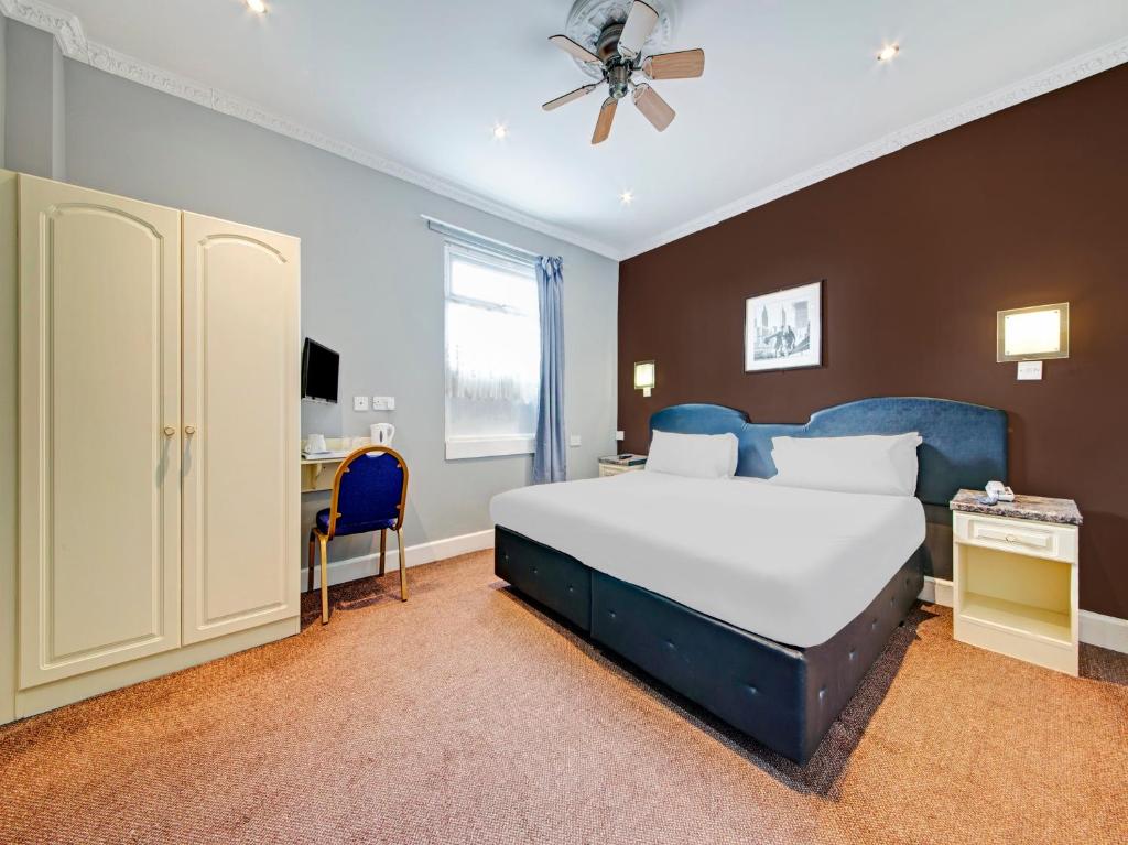 格林福德OYO Bostons Manor Hotel的一间卧室配有一张大床和一张书桌