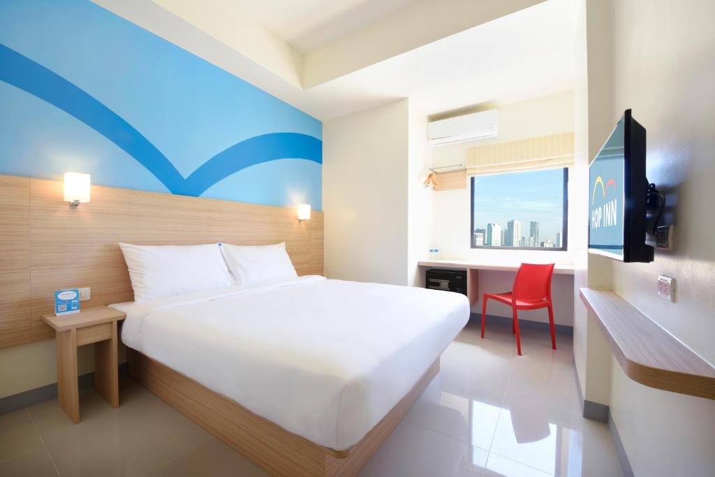 马尼拉Hop Inn Ortigas Center Manila的卧室配有一张白色大床和红色椅子
