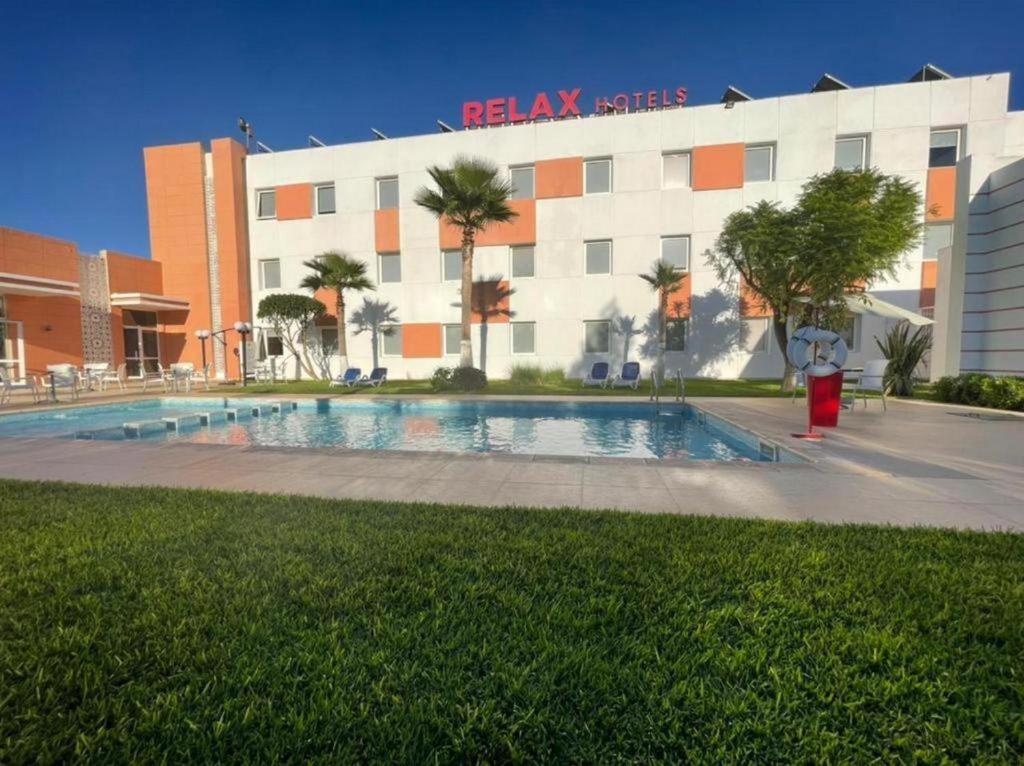 盖尼特拉Relax Hotel Kenitra的大楼前设有游泳池的酒店