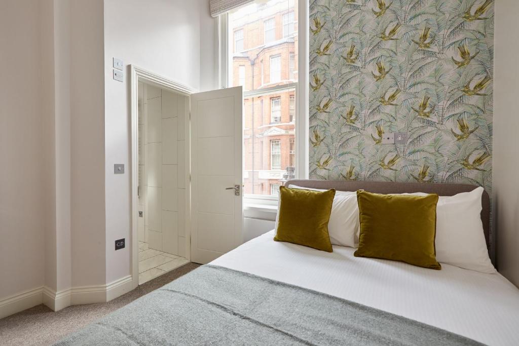 伦敦2VH Virginia House, 31 Bloomsbury Way by City Living London的一间卧室配有一张带黄色枕头的床和一扇窗户
