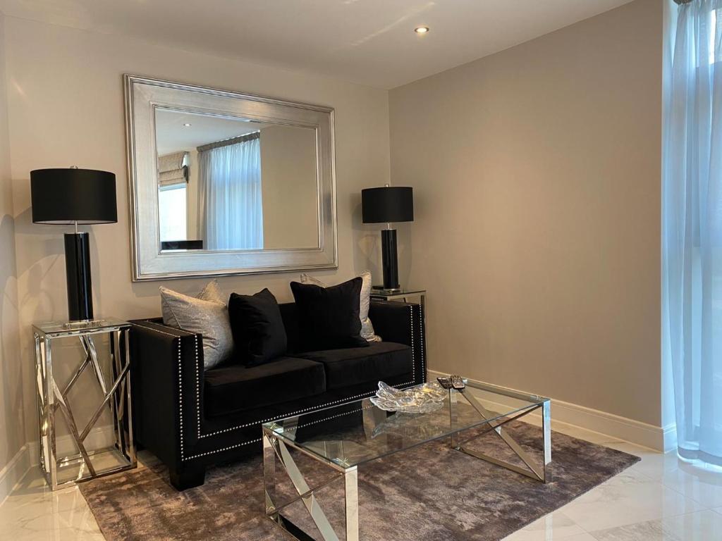 卡迪夫Exclusive Cardiff City Centre Apartment的客厅配有黑色沙发和镜子