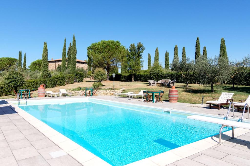 蒙特普齐亚诺Agriturismo Cavalierino的一个带桌椅和树木的游泳池