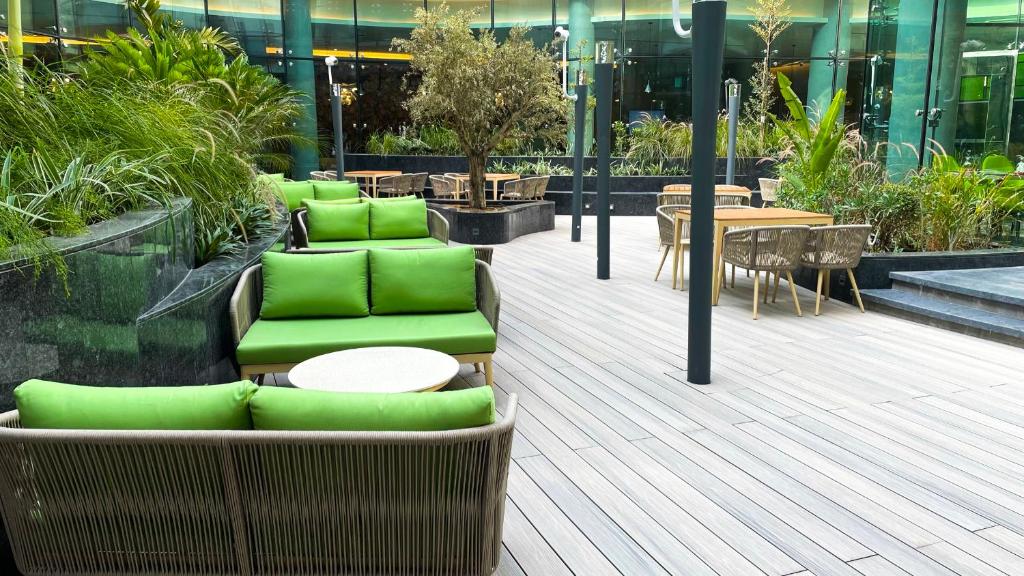 迪拜Al Khoory Sky Garden Hotel的一座带绿色桌椅的庭院