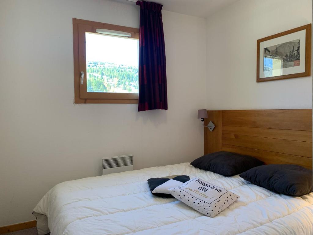 德沃吕伊Superdévoluy, appartement récent - en face et au pied des pistes的一张带两个枕头的床和一个窗户