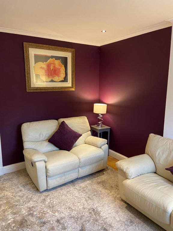 格拉斯哥Cheerful One bedroom cottage with parking space.的客厅配有2张白色沙发和紫色墙壁