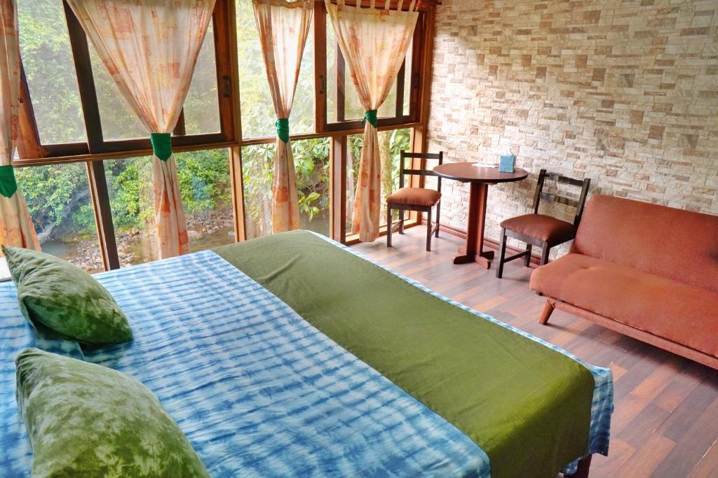 萨拉皮基La Quinta Sarapiqui Lodge的卧室配有床、桌子和窗户。